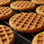 Waffle cookies cooling on a rack after pressing