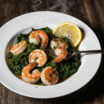 A bowl of food from the Ultimate Guide to 15-Minute Meals, featuring perfectly cooked garlic shrimp and spinach with a lemon wedge for garnish.