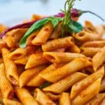 A close-up shot of a bowl of creamy tomato pasta, garnished with parmesan and basil. The rich, pink sauce coats the fettuccine perfectly, showcasing an easy and delicious recipe.